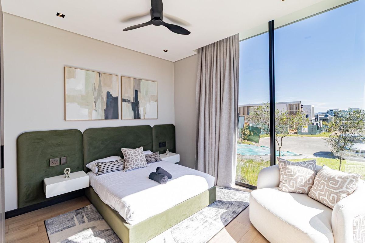 Modern bedroom featuring floor-to-ceiling windows, integrated headboard with floating bedside tables, recessed lighting, and a ceiling fan.