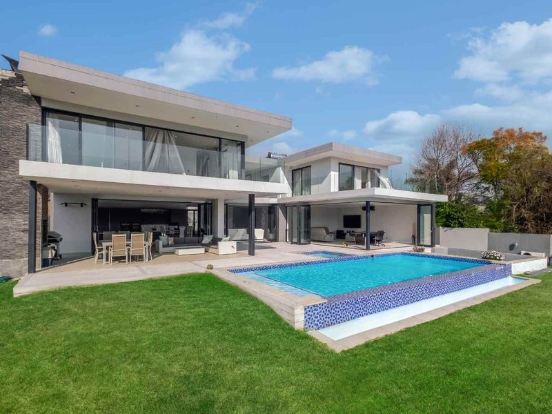 Modern rear exterior featuring a swimming pool, expansive covered patio, and seamless indoor-outdoor flow through large sliding glass doors.