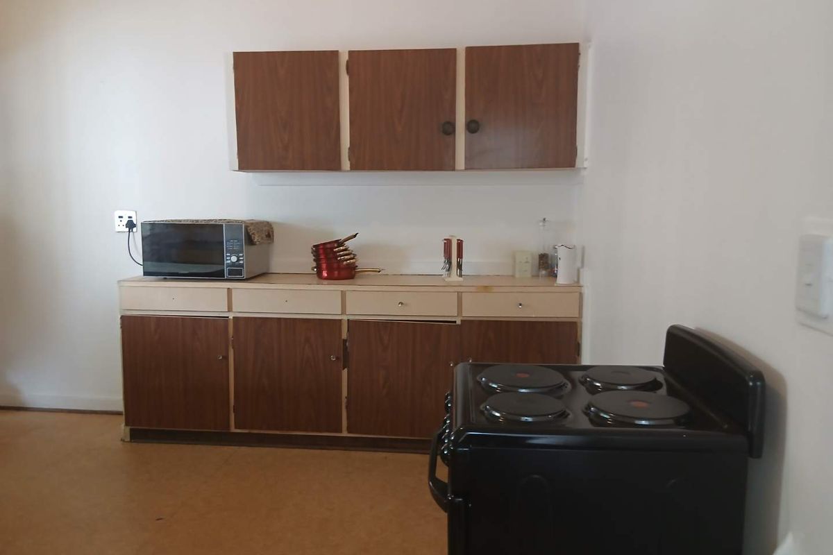 A functional kitchen area featuring dated wood-finish cabinetry and a freestanding electric stove.