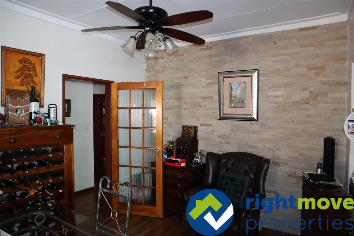 A living area featuring a textured stone feature wall, wooden door frames, and a ceiling fan.