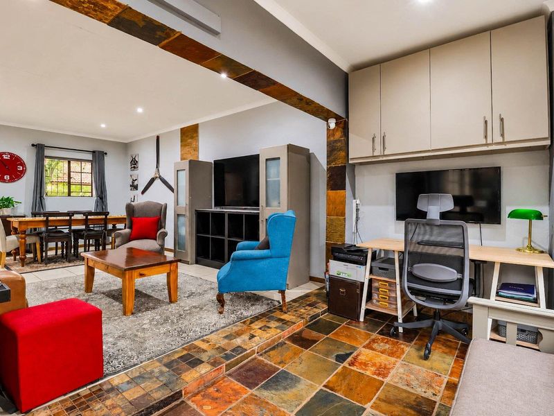 Spacious open-plan living area featuring slate tile flooring, built-in overhead storage cabinetry, and recessed lighting, creating a versatile space for living and home office use.