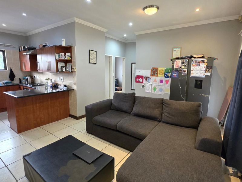 Open-plan living area featuring a functional kitchen with granite countertops, tiled flooring, and recessed lighting, seamlessly connected to the main living space.