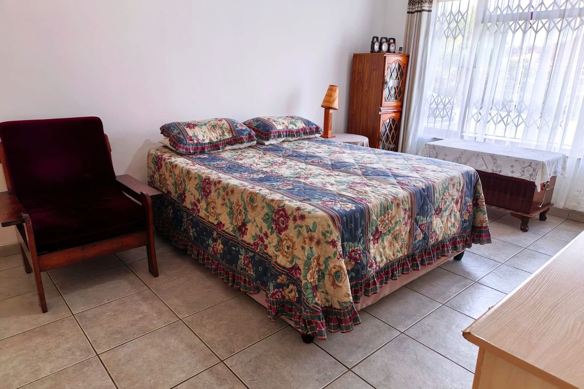 A bedroom featuring tiled flooring and a window fitted with a security gate, offering a functional and well-lit space.