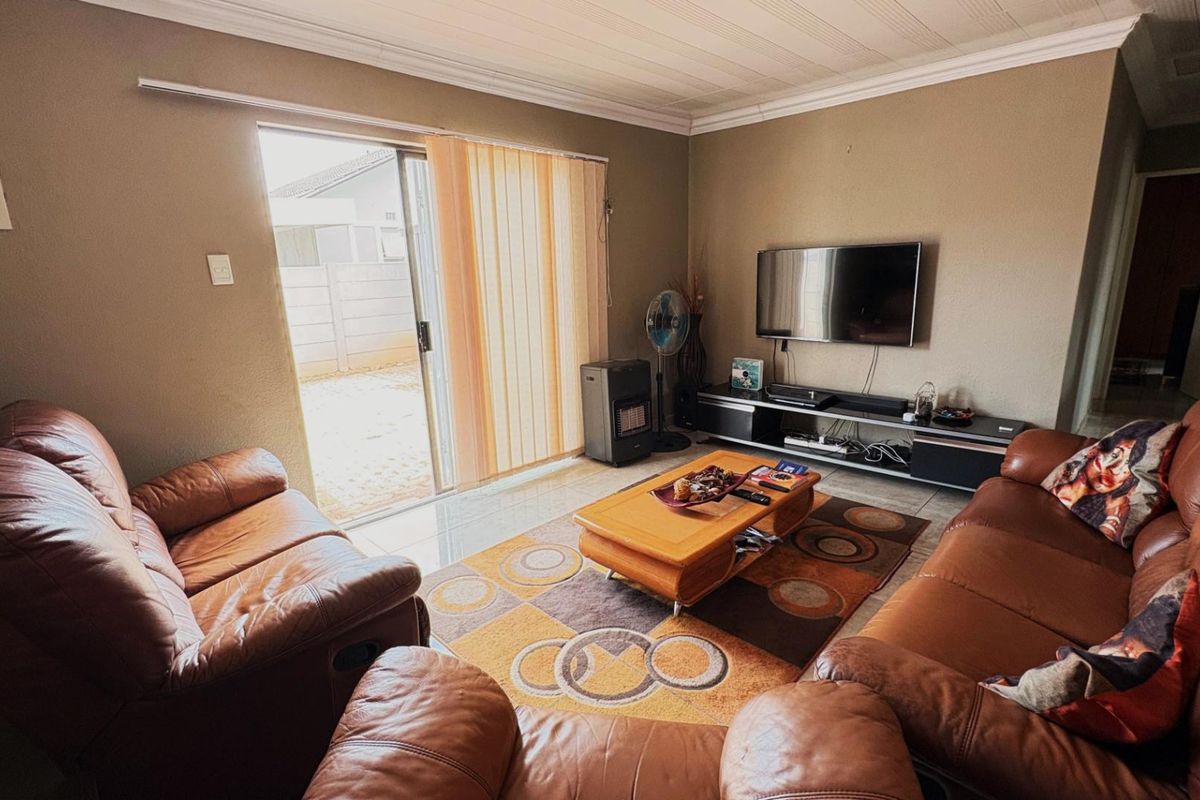 A comfortable living room featuring tiled flooring, neutral wall tones, and a sliding glass door providing direct access to the rear outdoor area.