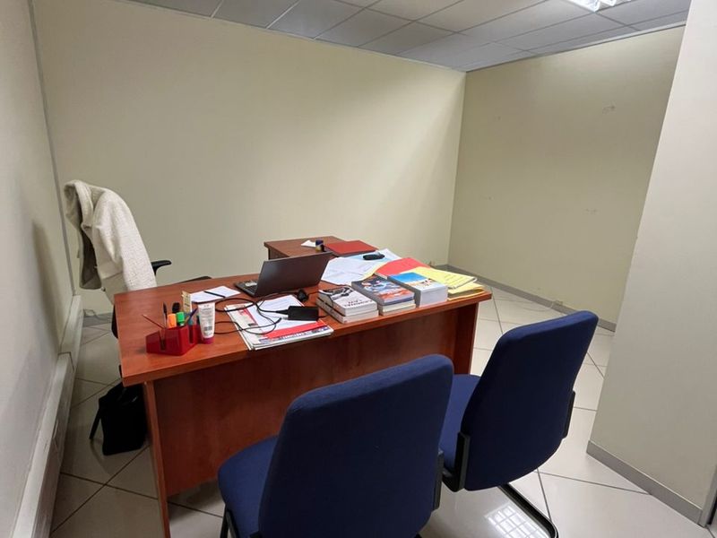 A functional office space featuring a suspended ceiling with recessed lighting and durable ceramic tile flooring.