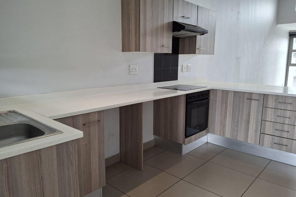 Modern kitchen featuring wood-look laminate cabinetry, stone countertops, built-in oven, electric hob, extractor fan, and neutral tiled flooring.