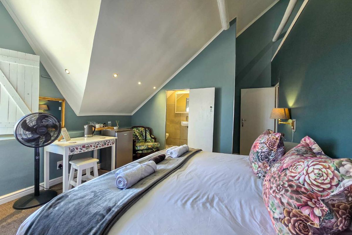 A bedroom featuring a vaulted ceiling, recessed lighting, and an en-suite bathroom with tiled finishes.