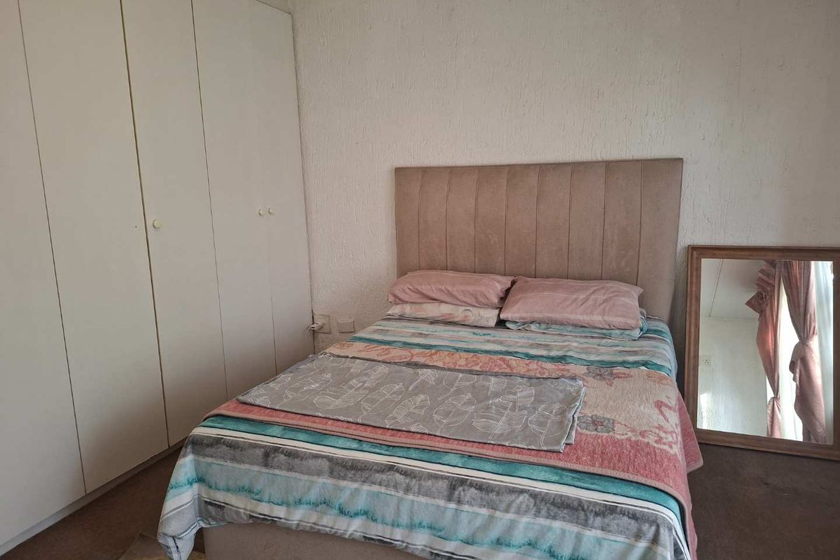 A bedroom featuring built-in floor-to-ceiling wardrobes and carpeted flooring, providing functional storage space.