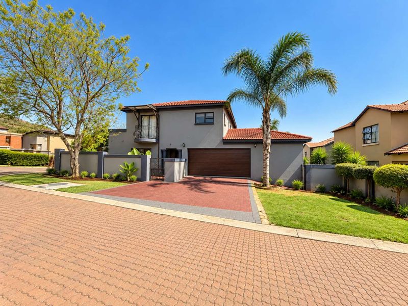 A well-maintained double-story residential property featuring a paved driveway, double garage, and a balcony with a tiled roof.