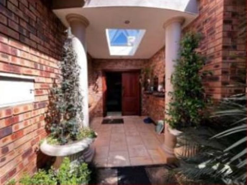 Front entrance featuring a brick facade, decorative columns, tiled flooring, and a skylight above the timber front door.