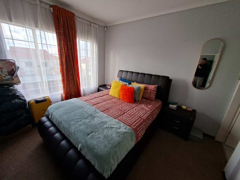 A well-lit bedroom featuring carpeted flooring, a large window with natural light, and coved ceiling details.