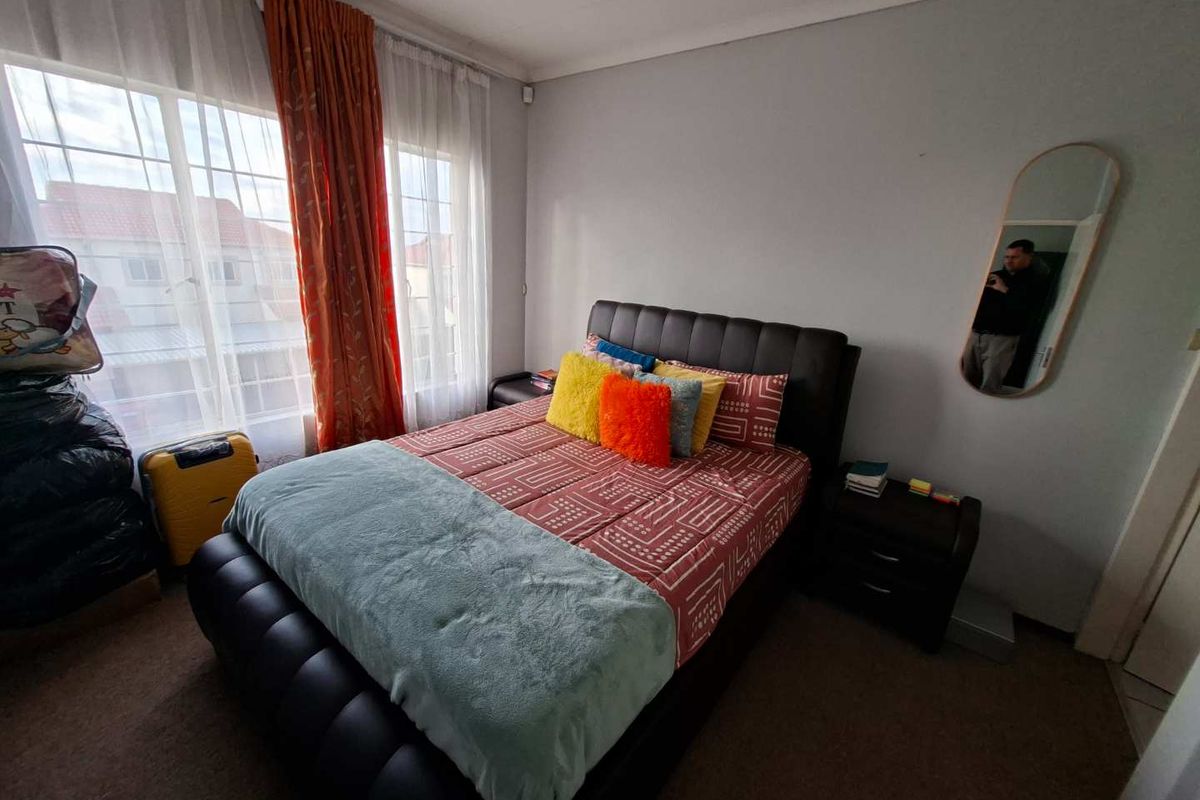 A well-lit bedroom featuring carpeted flooring, a large window with natural light, and coved ceiling details.