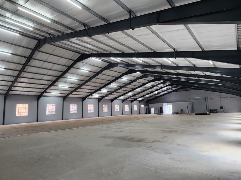 Spacious industrial warehouse featuring a high-clearance steel portal frame, polished concrete flooring, ample natural light from glass block windows, and integrated overhead lighting.