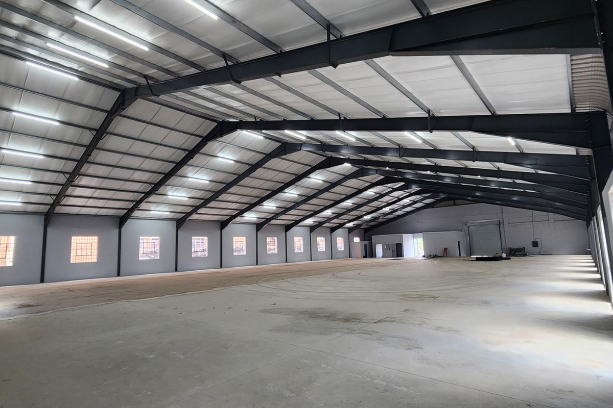 Spacious industrial warehouse featuring a high-clearance steel portal frame, polished concrete flooring, ample natural light from glass block windows, and integrated overhead lighting.