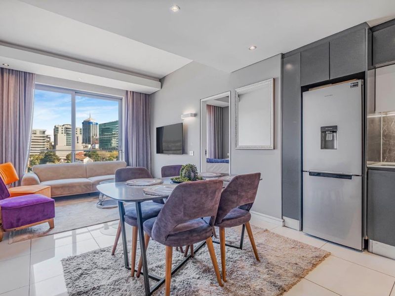 Modern open-plan living and kitchen area featuring sleek cabinetry, tiled floors, and large sliding doors with expansive city views.