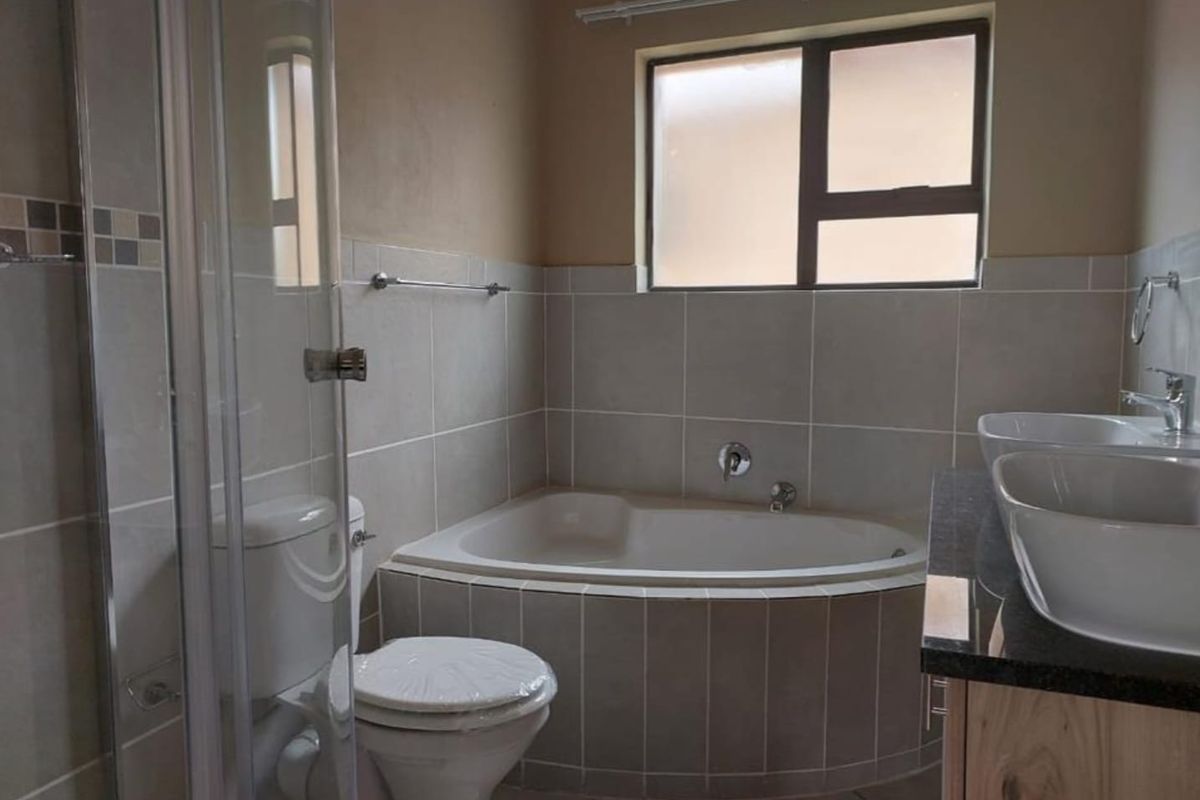 A functional bathroom featuring a corner bathtub, a glass-enclosed shower, and a double vanity with modern vessel sinks.