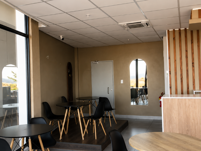 A modern open-plan retail or cafe space featuring a suspended ceiling, tiled flooring, a raised timber platform, and decorative timber slat wall paneling.
