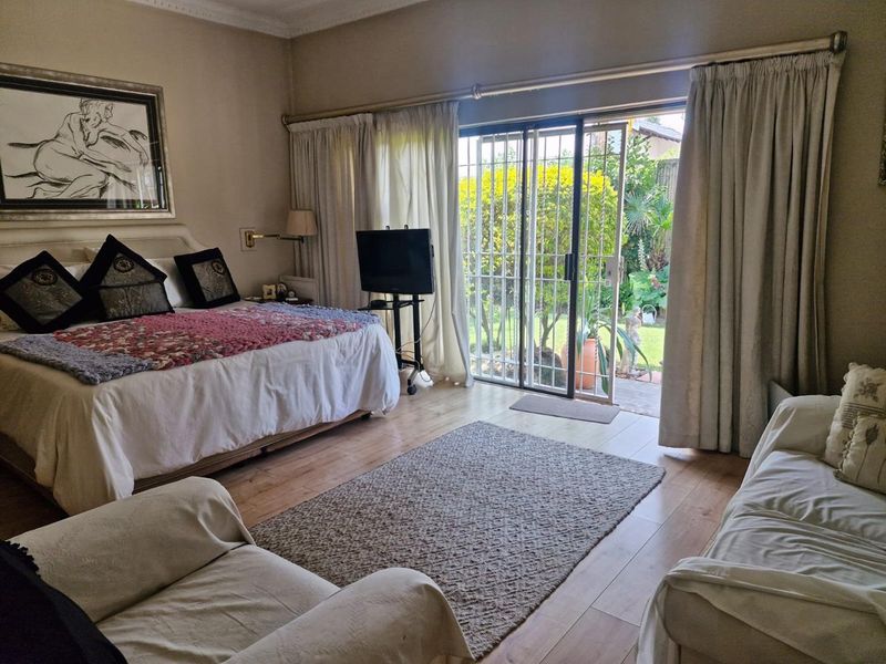 Spacious bedroom featuring laminate flooring, crown molding, and a sliding glass door providing direct access to the garden.