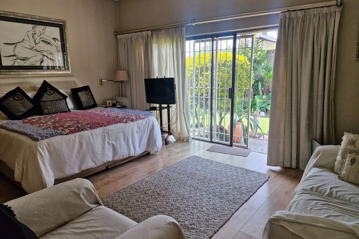 Spacious bedroom featuring laminate flooring, crown molding, and a sliding glass door providing direct access to the garden.