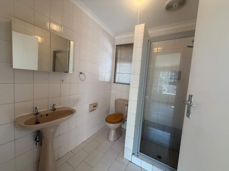 A functional bathroom featuring a pedestal basin, toilet, and a separate shower enclosure with tiled finishes throughout.