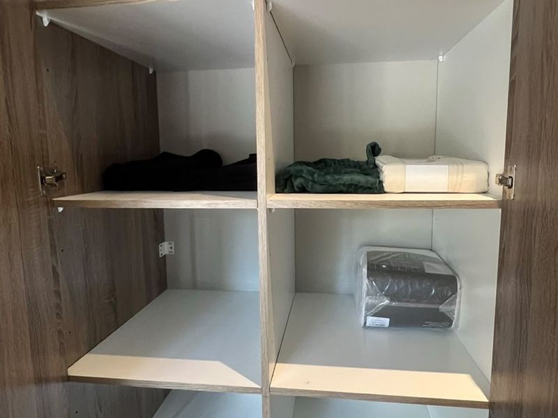A view inside a clean, modern built-in bedroom wardrobe featuring multiple storage shelves.