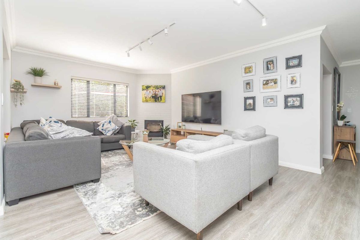 A bright and modern living room featuring light wood-look flooring, a built-in fireplace, and track lighting.