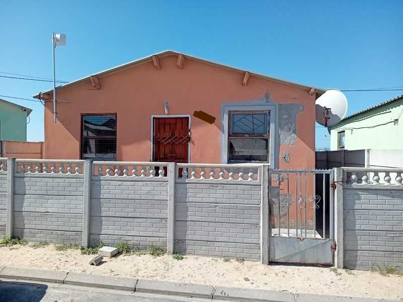 Front elevation of a single-story house featuring a precast concrete boundary wall, metal pedestrian gate, and a peach-colored exterior facade.