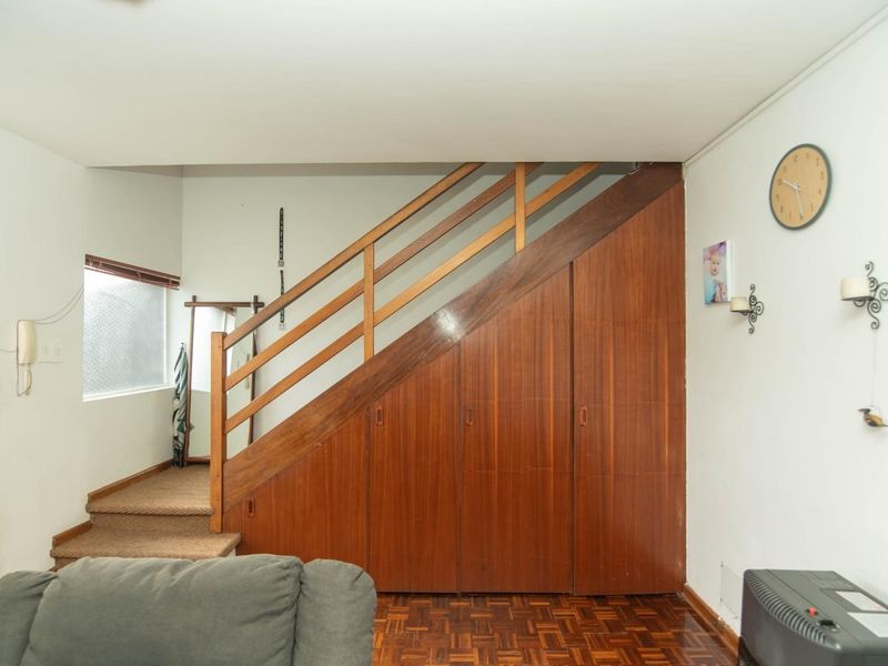 Hallway area featuring a wooden staircase with integrated under-stair storage cabinetry and classic parquet flooring.
