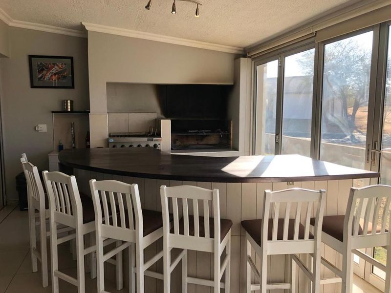 Indoor entertainment area featuring a built-in braai, curved bar counter, and large sliding glass doors providing natural light and outdoor access.