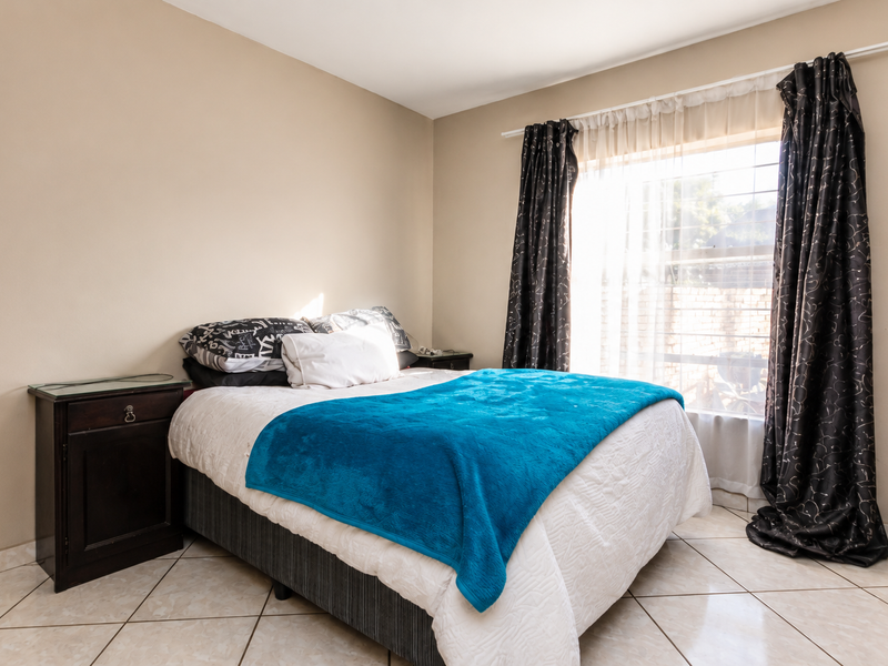 A bedroom featuring neutral wall tones, tiled flooring, and a window with installed curtain rods.