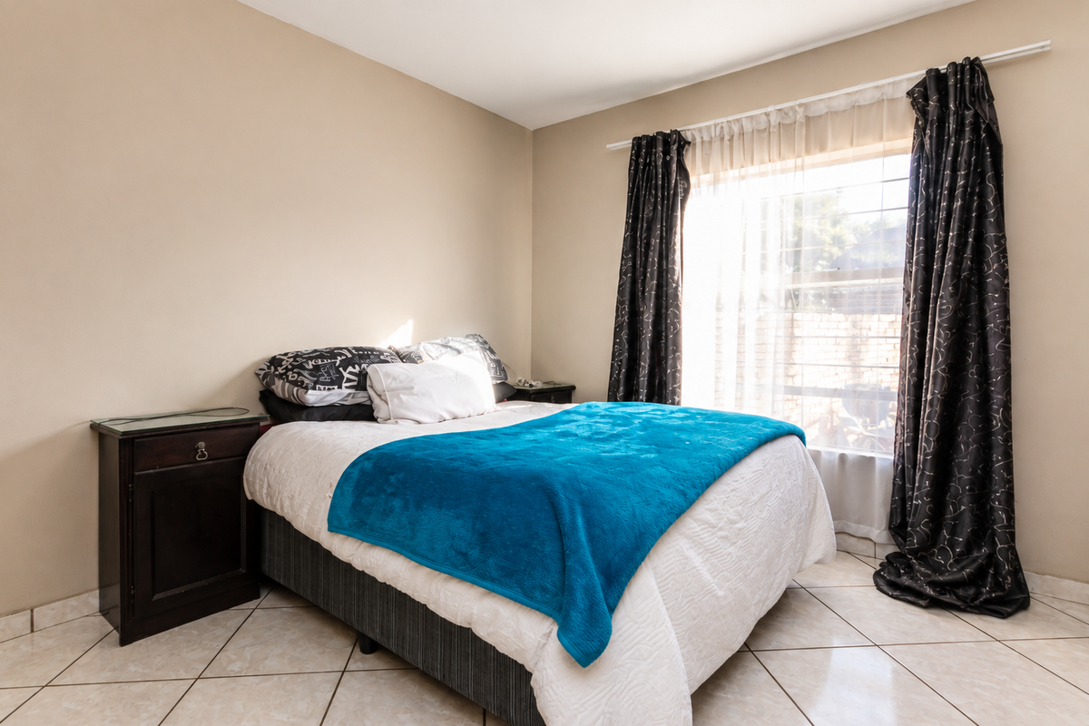 A bedroom featuring neutral wall tones, tiled flooring, and a window with installed curtain rods.