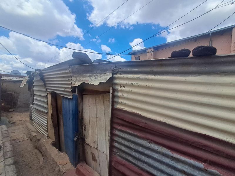 Exterior view of a structure featuring corrugated iron wall cladding and a timber entrance door.