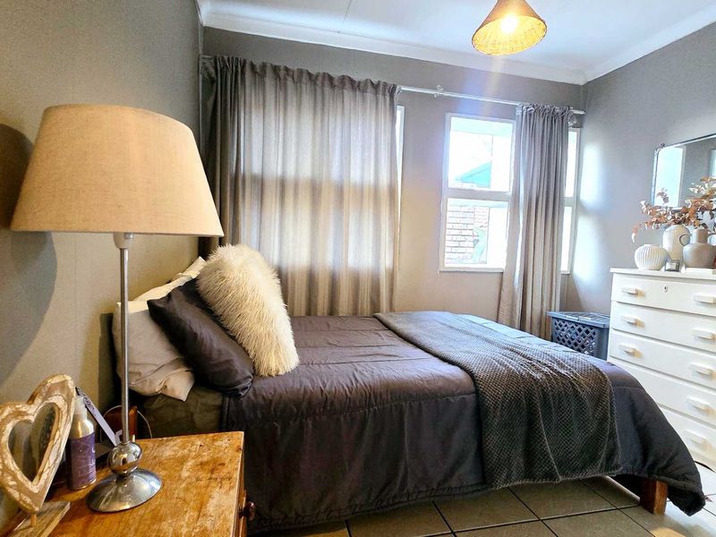 A cozy bedroom featuring tiled flooring, neutral wall tones, and a built-in mirror, offering a functional and comfortable living space.
