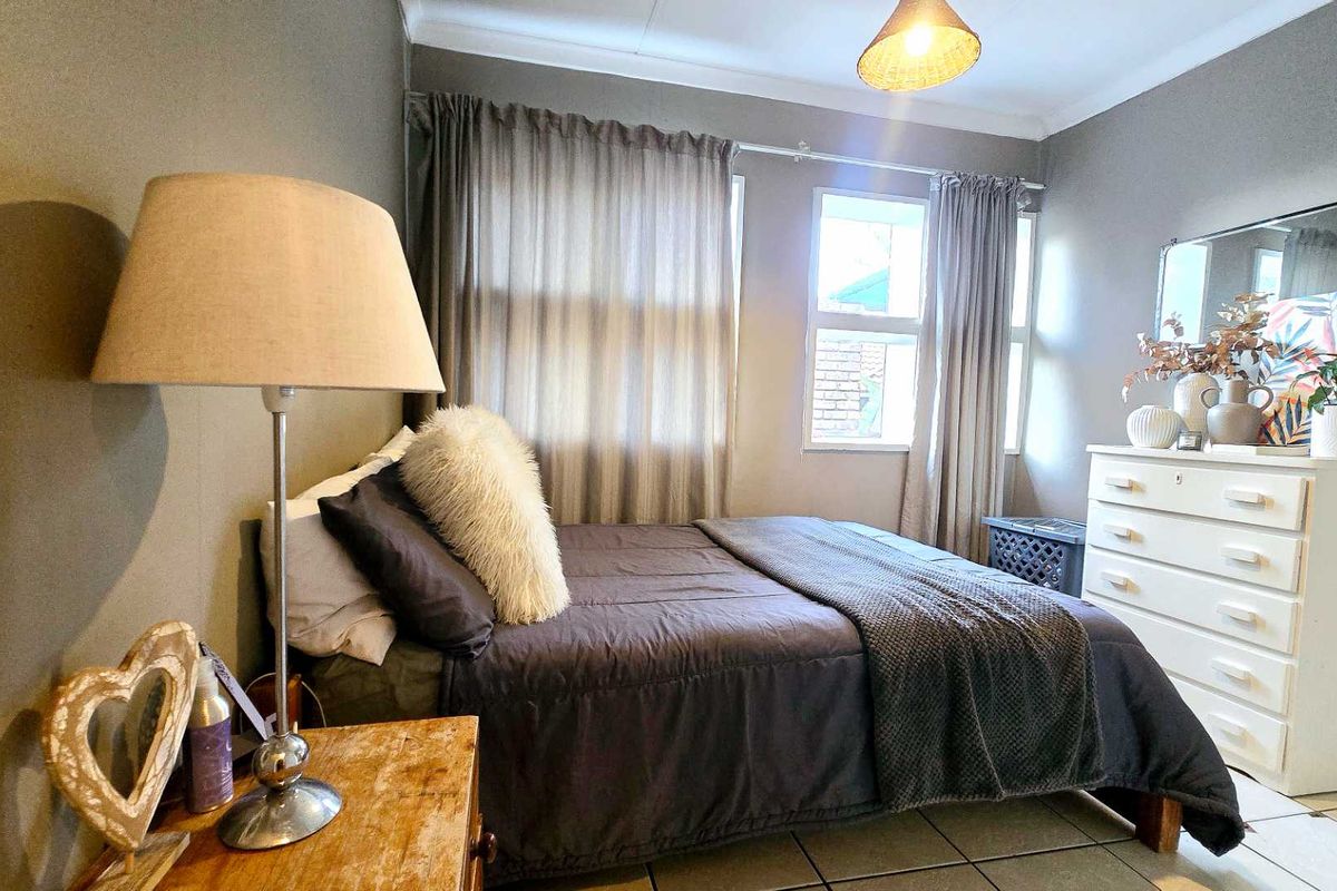 A cozy bedroom featuring tiled flooring, neutral wall tones, and a built-in mirror, offering a functional and comfortable living space.