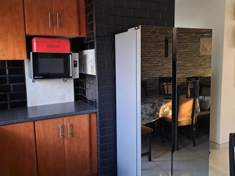 A kitchen area featuring wooden cabinetry, a black subway tile backsplash, and a laminate countertop with a dedicated built-in microwave space.