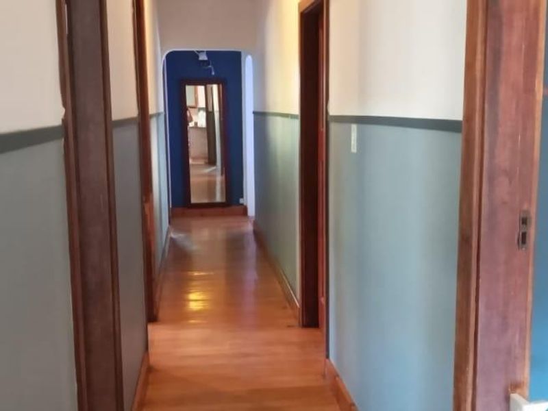 A long hallway featuring polished hardwood flooring and timber door frames, finished with a two-tone wall paint scheme.