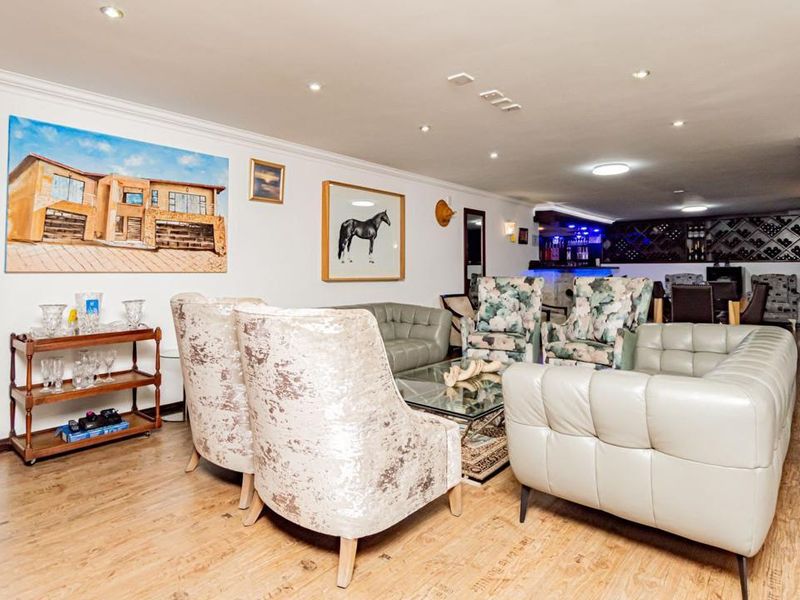 Spacious entertainment area featuring a built-in bar with integrated wine storage, recessed lighting, and durable laminate flooring.