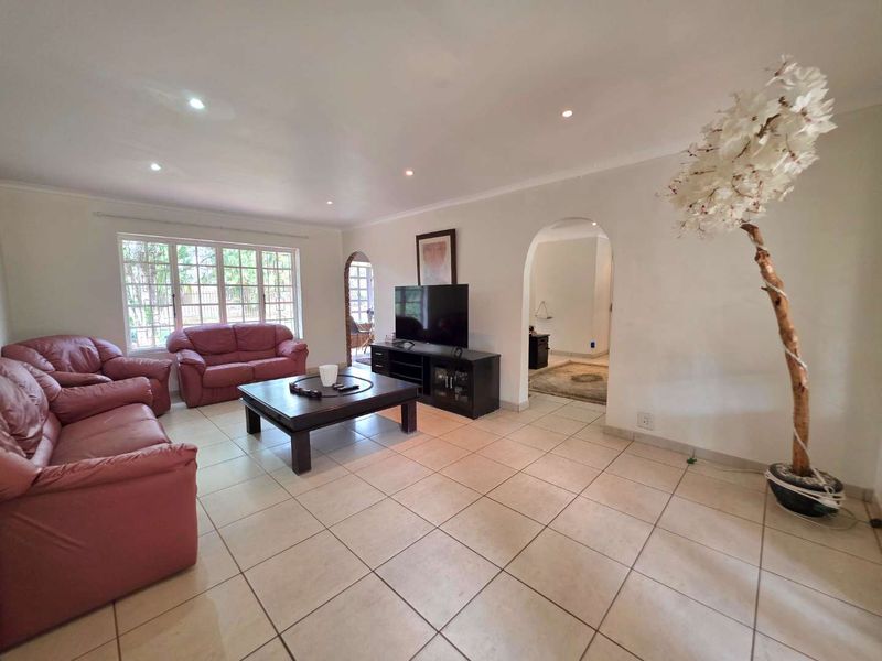 Spacious living room featuring neutral tiled flooring, recessed downlighting, and an arched entryway leading to adjacent living spaces.