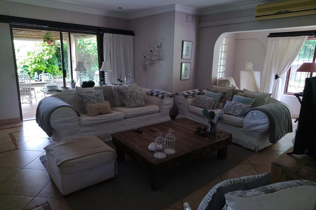 Spacious living room featuring tiled flooring, coved ceilings, and large sliding glass doors providing direct access to the outdoor patio area.