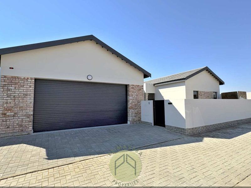 Modern residential exterior featuring a double garage, paved driveway, and clean brick and plaster facade finishes.