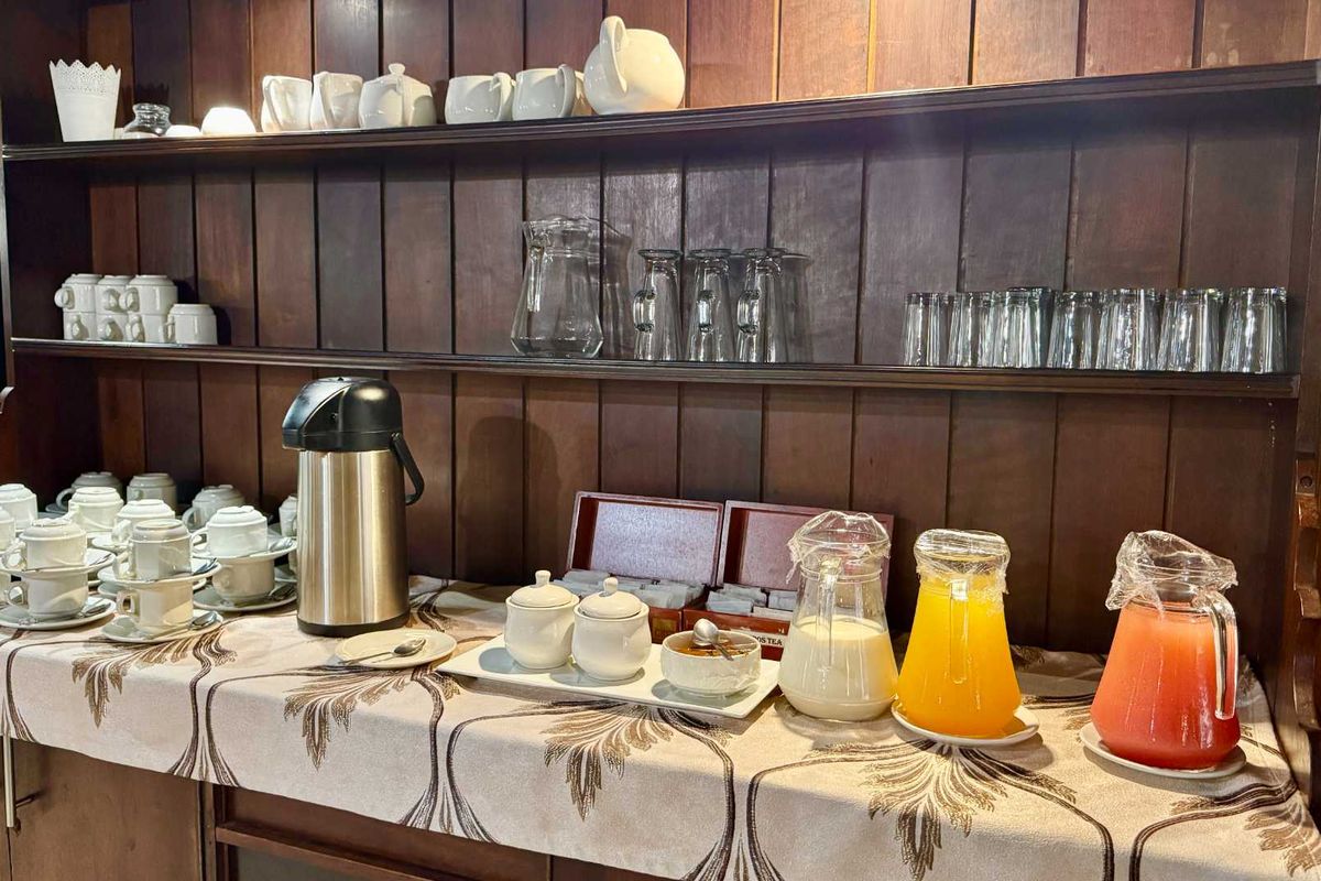 A breakfast station featuring built-in dark wood shelving and cabinetry, providing a functional space for beverage and refreshment service.