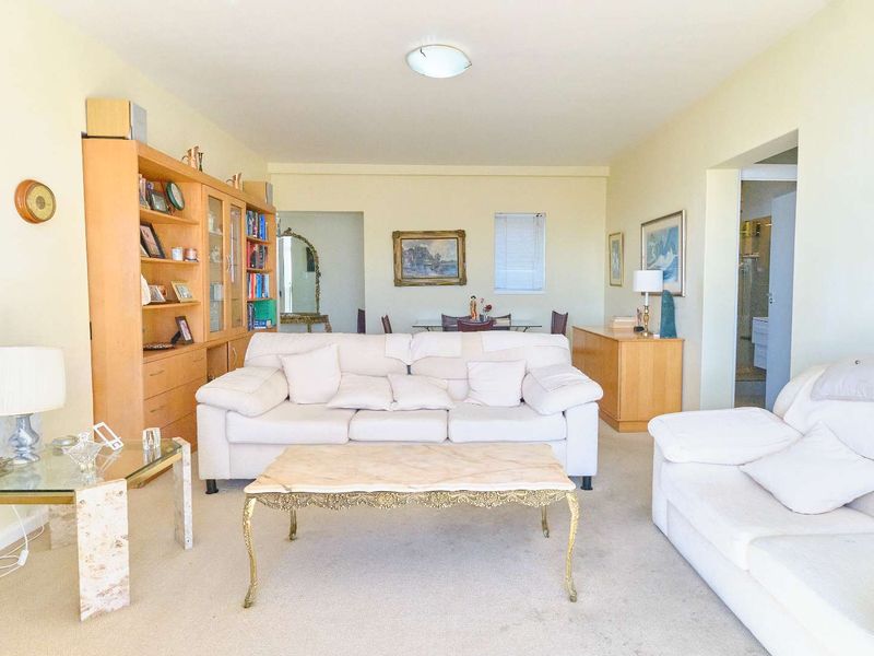 Spacious living room featuring neutral carpeting and a large built-in shelving unit, offering a comfortable and functional layout for relaxation.