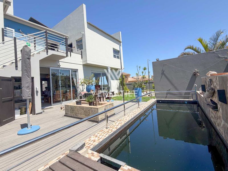 Outdoor pool area featuring composite decking, stainless steel railings, and direct access to the home via sliding glass doors and an external staircase.