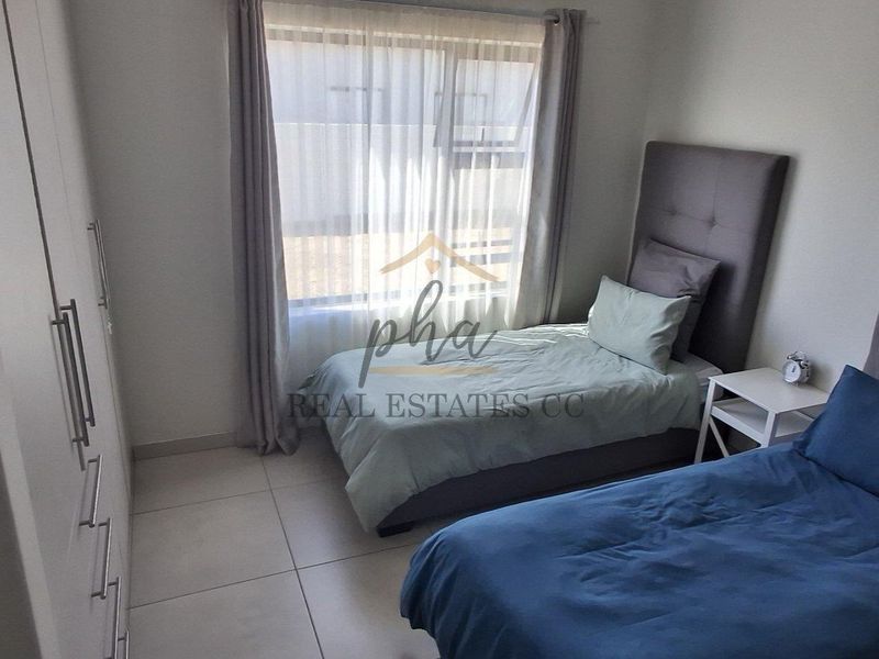 A well-maintained bedroom featuring neutral tiled flooring and ample built-in cupboard storage, providing a clean and functional living space.