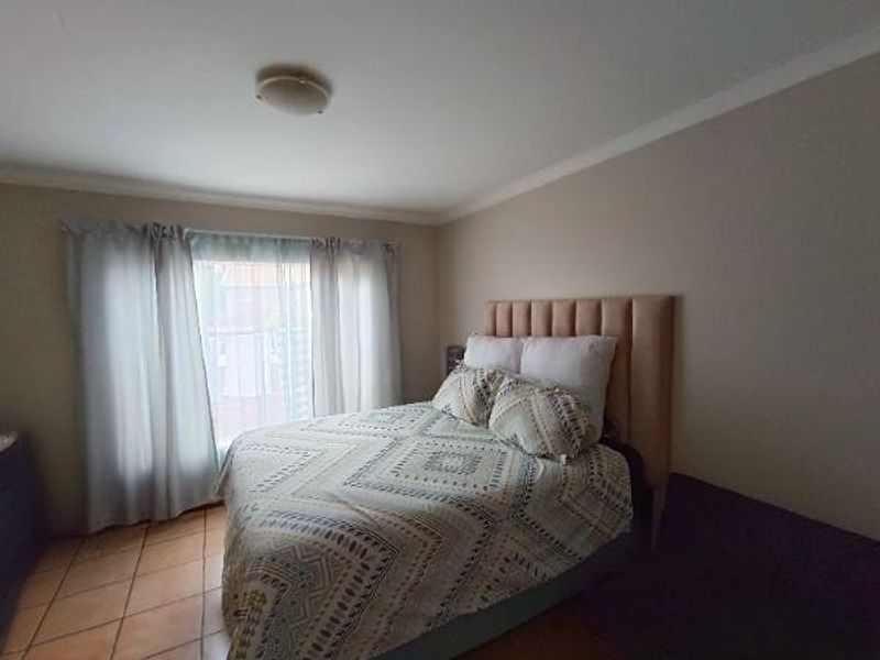 A bedroom featuring tiled flooring and a neutral wall finish, providing a functional space with natural light from the window.