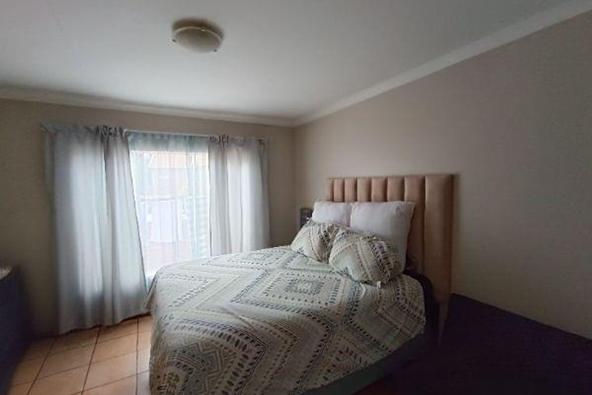 A bedroom featuring tiled flooring and a neutral wall finish, providing a functional space with natural light from the window.