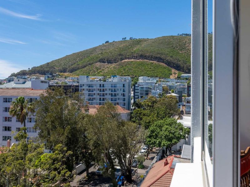 An elevated urban view overlooking the surrounding neighborhood with a prominent mountain backdrop, captured from an apartment window.