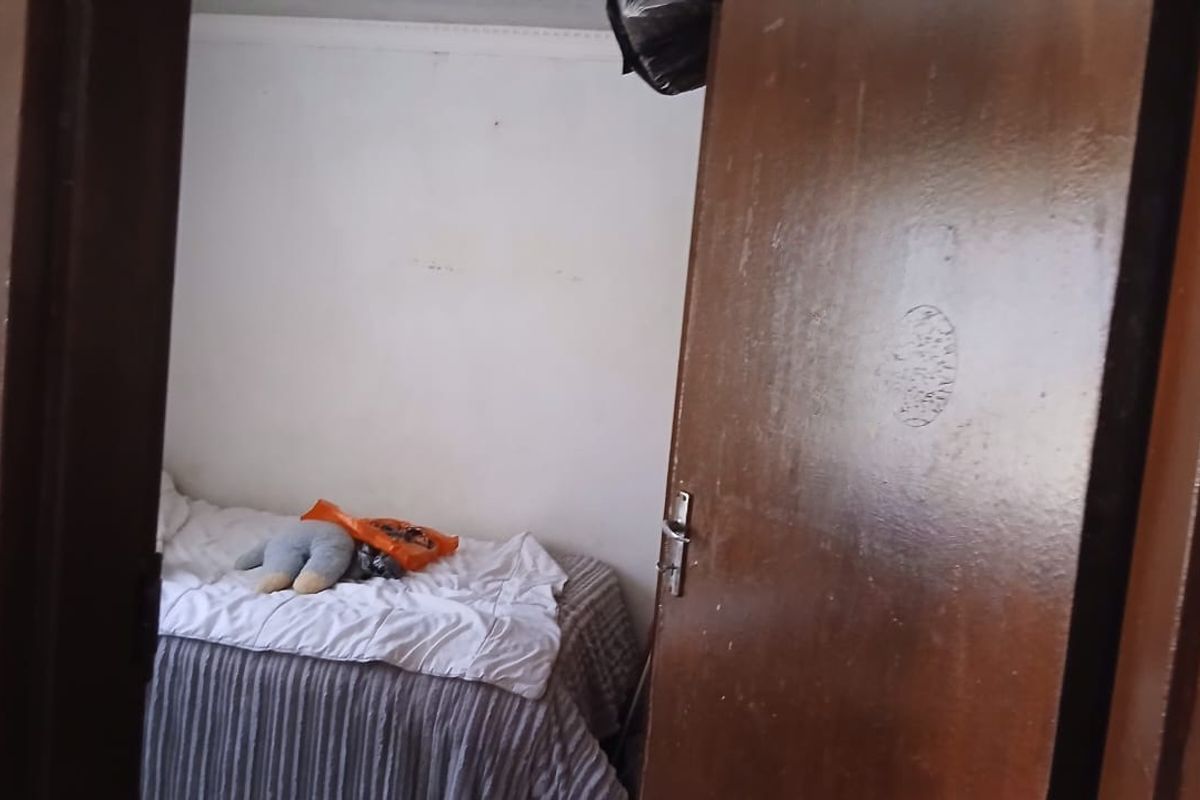 A view into a bedroom featuring a wooden door and basic interior finishes, showing signs of wear and requiring cosmetic updates.