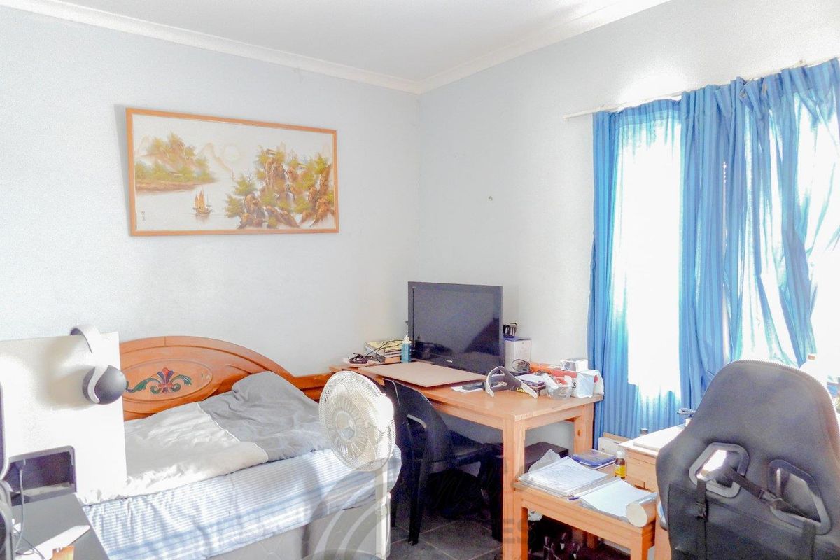 A bedroom featuring tiled flooring and a window with curtain fixtures.