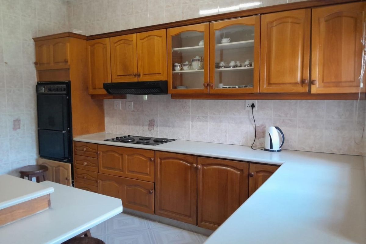 A functional kitchen featuring traditional wooden cabinetry, built-in oven, gas hob, and tiled backsplash, offering a classic layout with ample counter space.